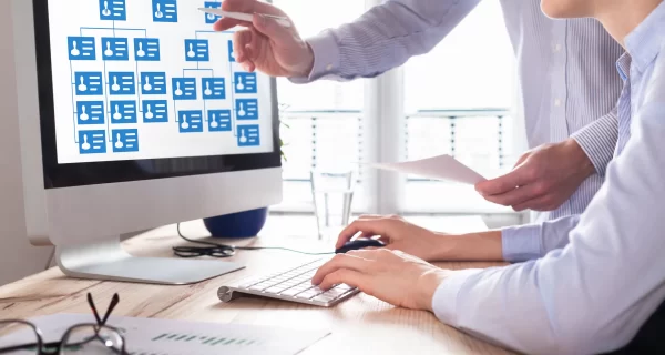 Organization chart with hierarchy structure of teams and employees in company. Human Resources Managers working with HR organizational diagram on computer screen in office, career concept